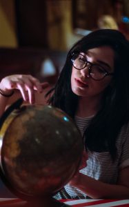 Femme avec lunettes en train de tourner un globe terrestre