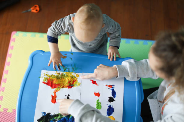 Nounou qui apprend à un enfant à peindre