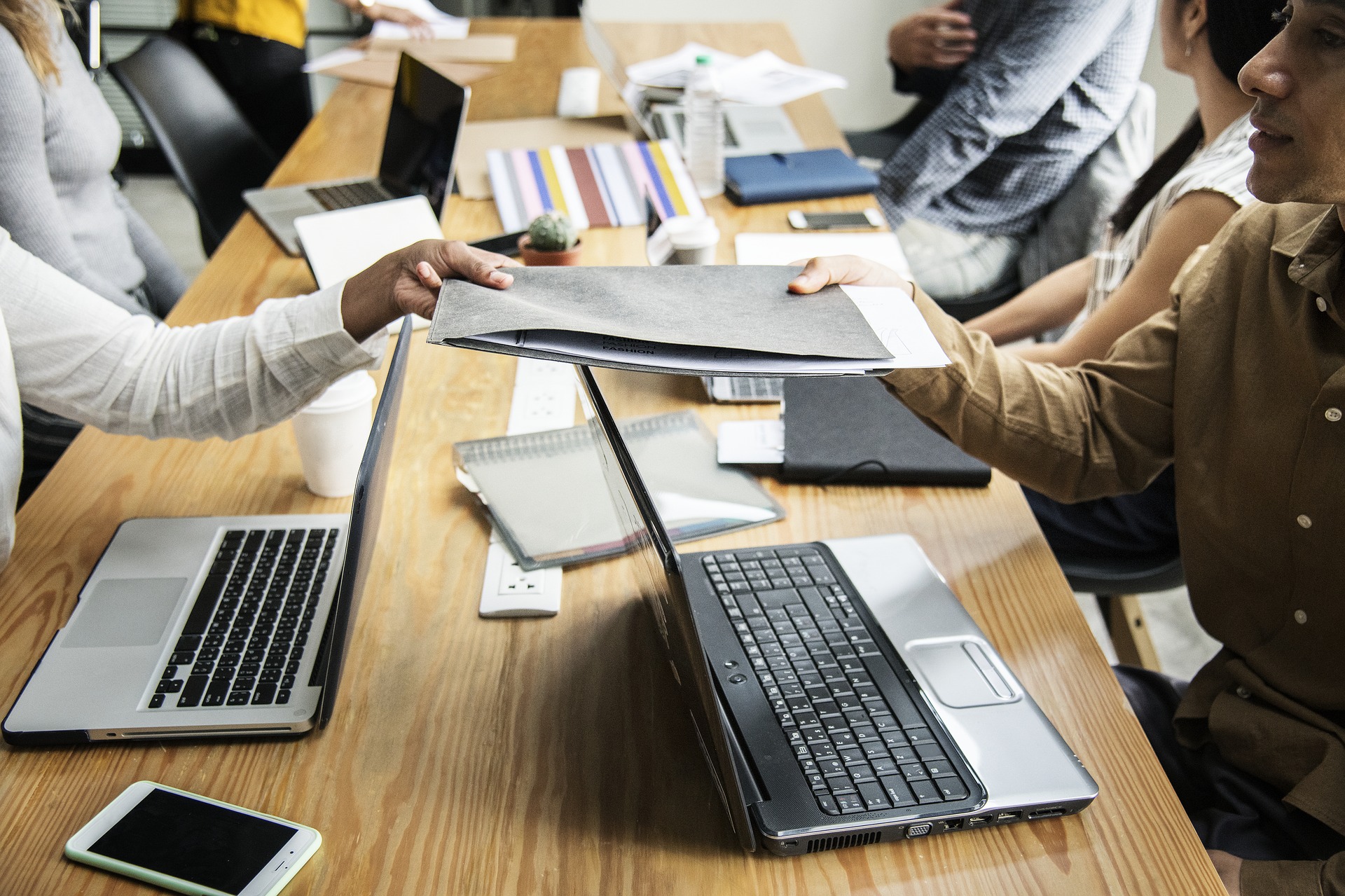 Personnes avec des ordinateurs portables assises autour d'une longue table